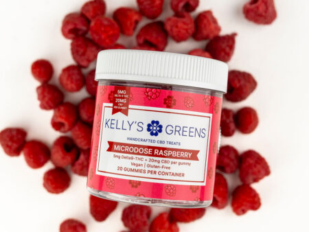 A jar of Delta 9 5mg raspberry gummies surrounded by raspberries on a white background.